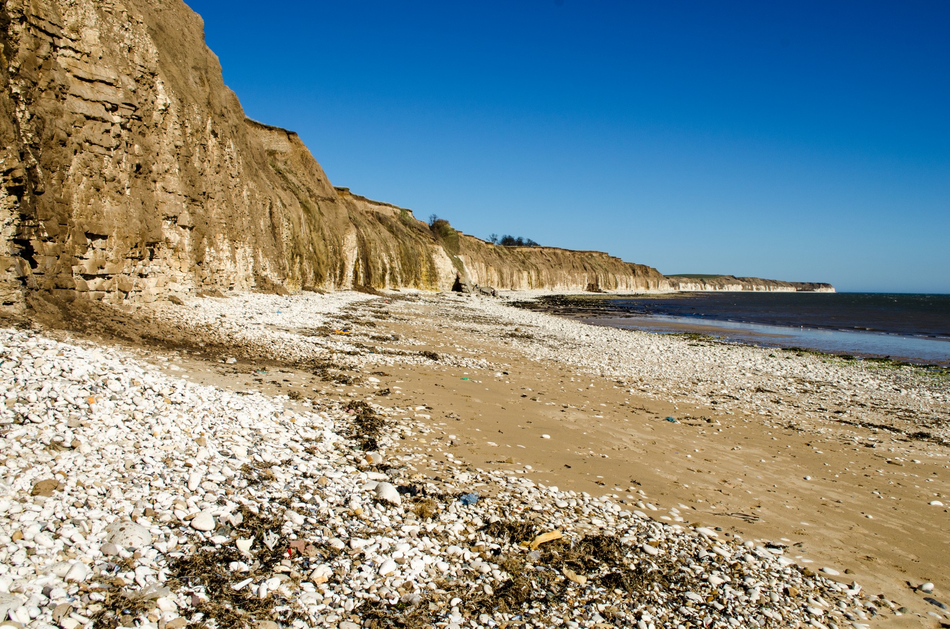 Берег лове. Камни на пляже. Слоистый песок на побережье. Анаклия берег с песком. Приморская волна.